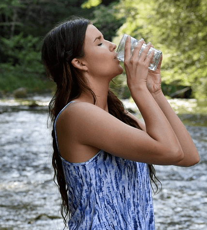 girl drinking water in river